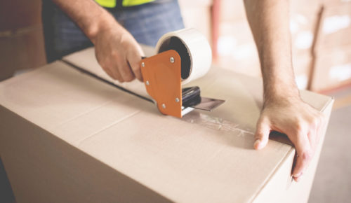 Man properly packing his shipment using tape roller to seal a box