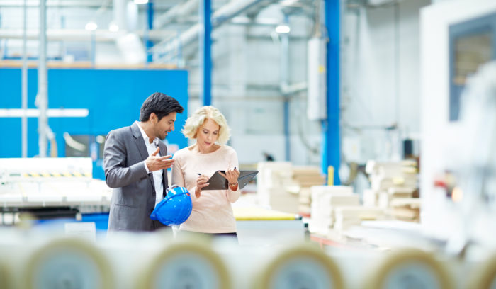 man and woman review clipboard in warehouse - logistics