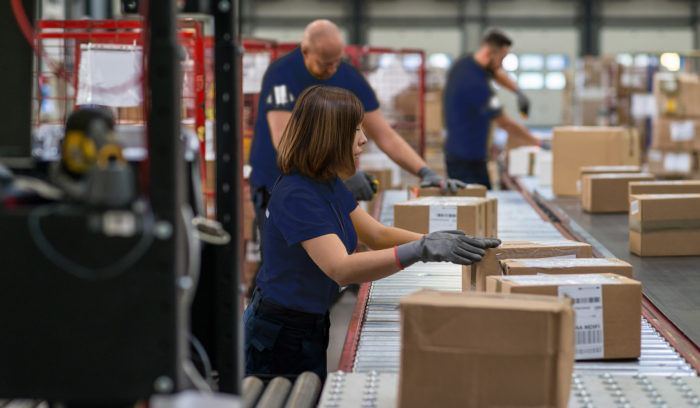 supply chain, men and women preparing shipments on conveyor belt