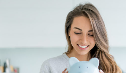 women smiling at piggy bank, saving money