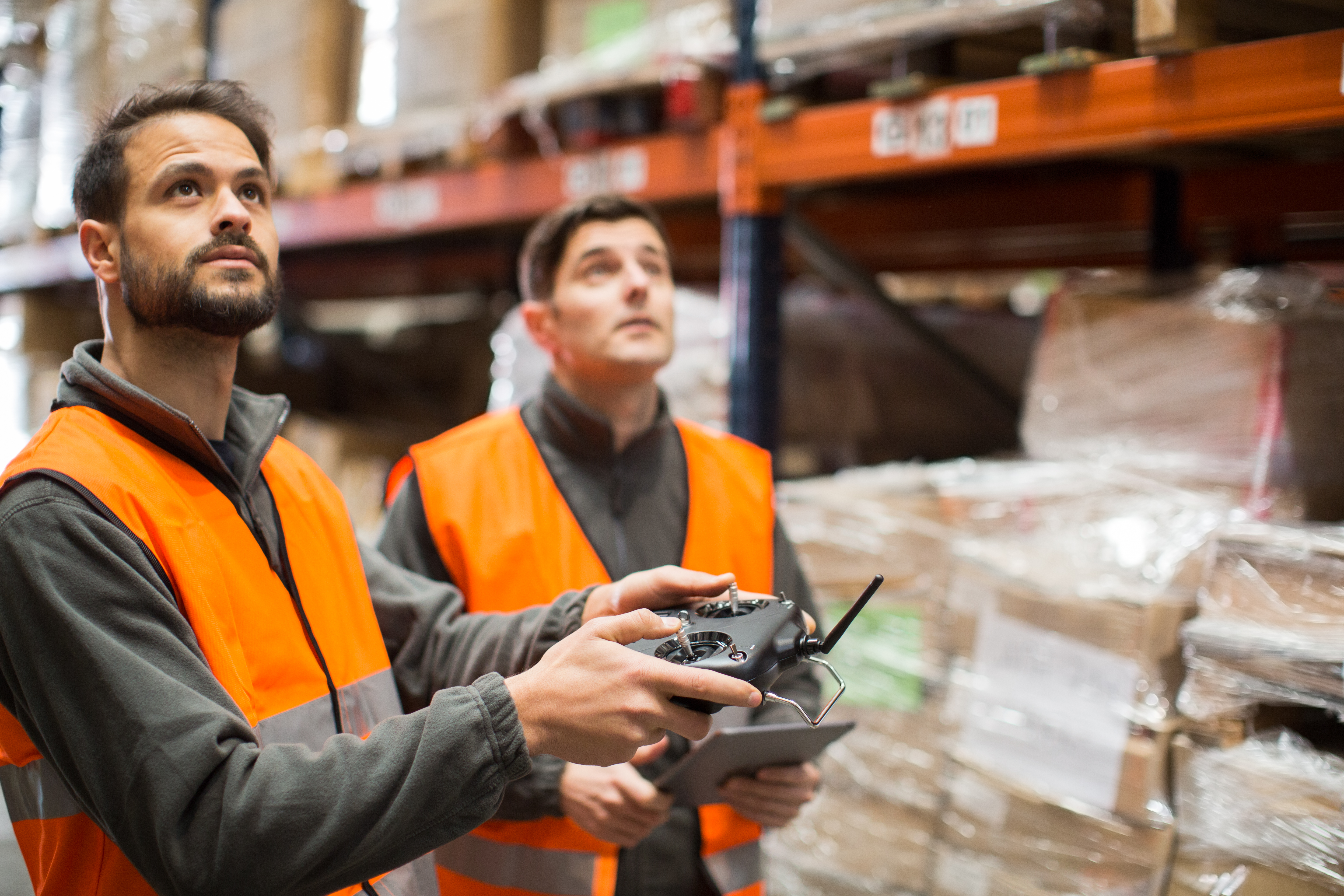 Two warehouse workers stocktaking warehouse inventory with drone, shipping and delivery logistic trends