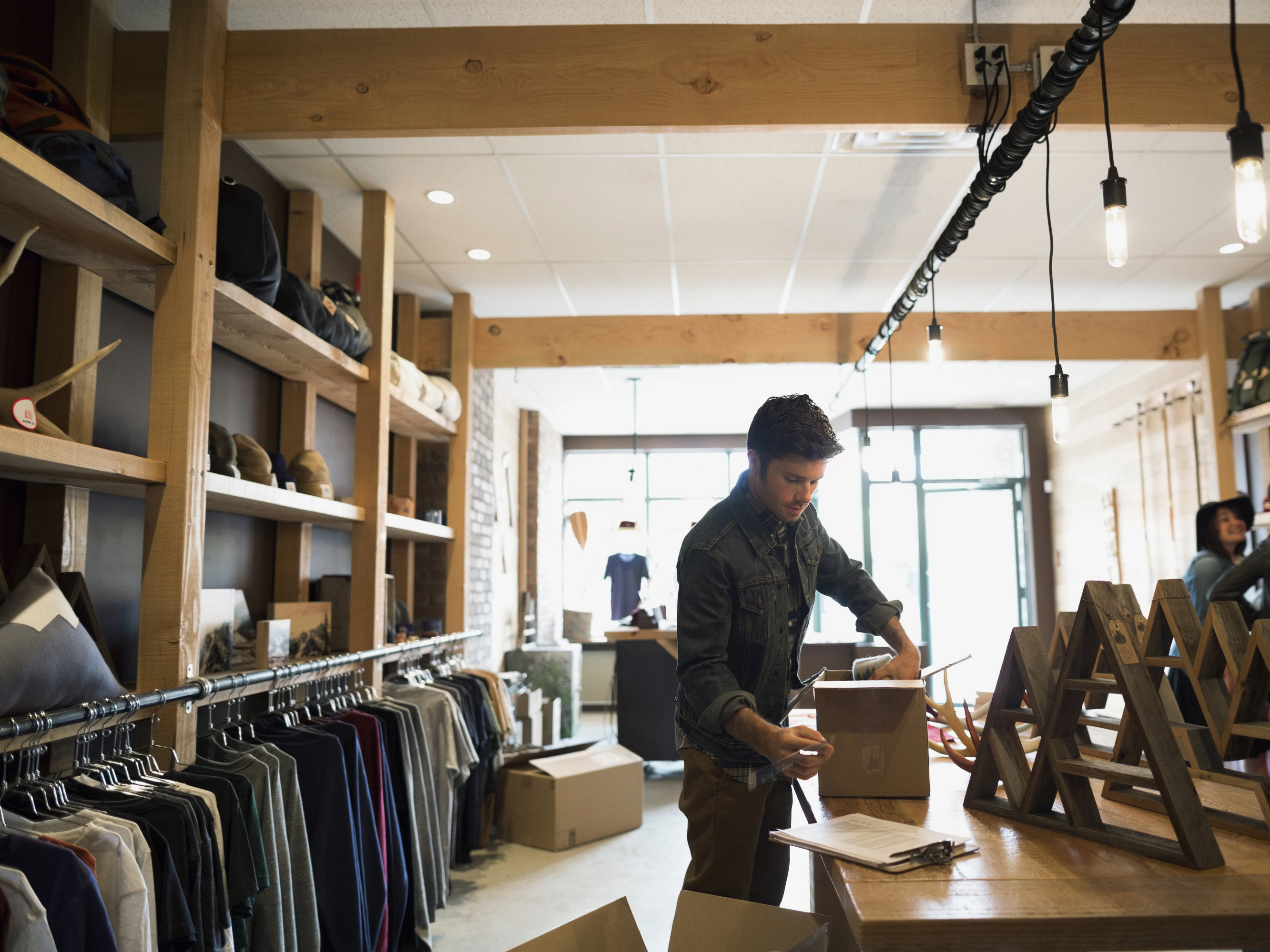 man in retail store packing delivery box, improving the last mile of delivery experience