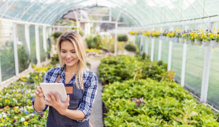 happy woman in flower garden with her tablet scaling a business
