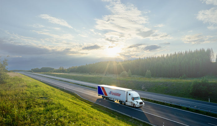 Purolator freight truck driving on a road and importing in to Canada