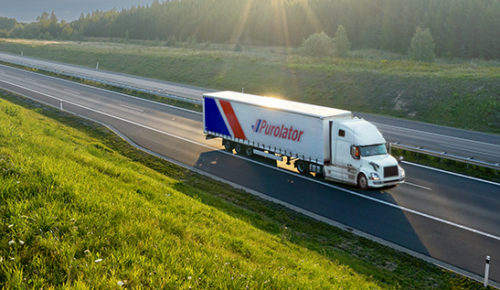Purolator freight truck driving on a road and importing in to Canada