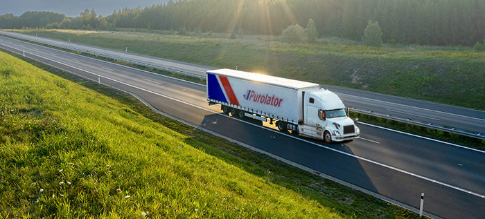 Purolator freight truck driving on a road and importing in to Canada