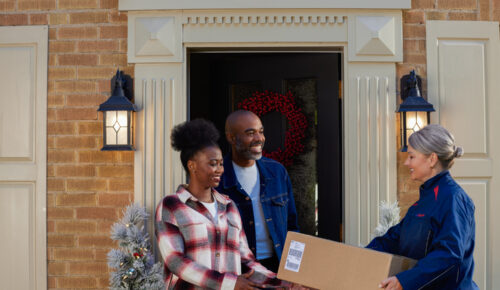 Couple greeting Purolator courier at front during during holiday shipping