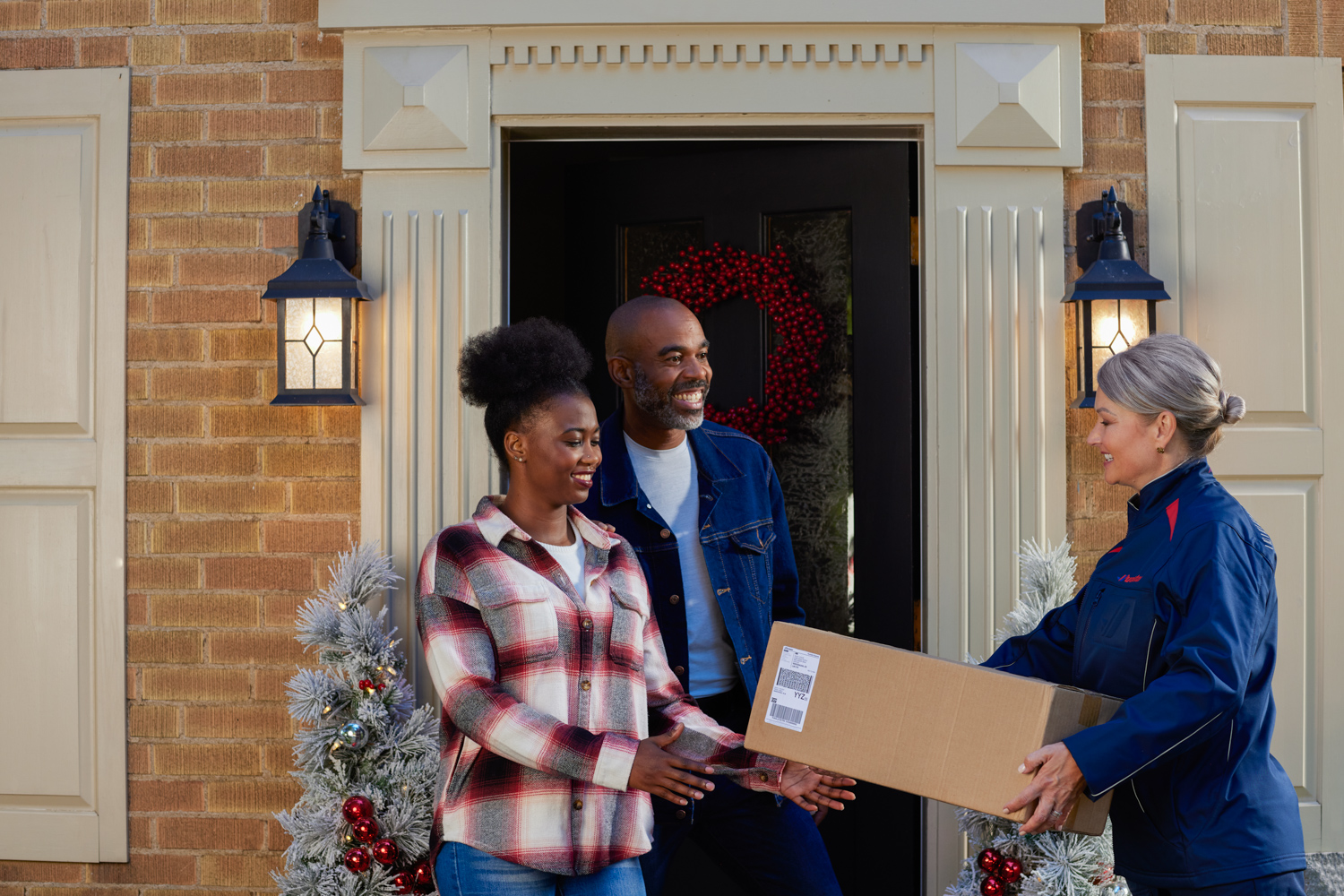 Couple greeting Purolator courier at front during during holiday shipping